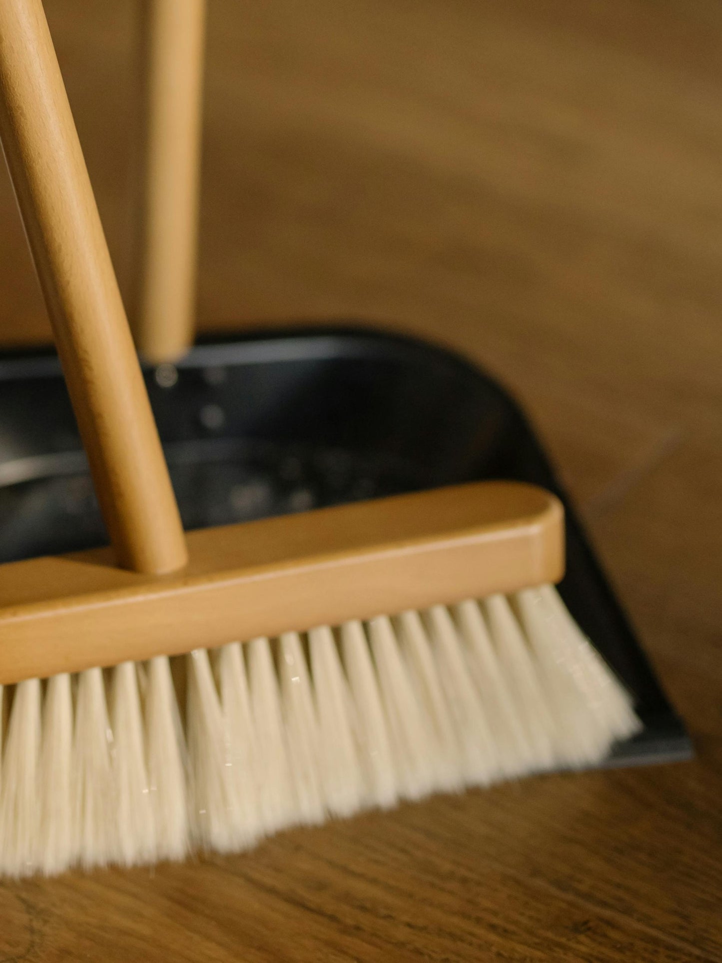 Wooden broom and dustpan set on a wooden floor